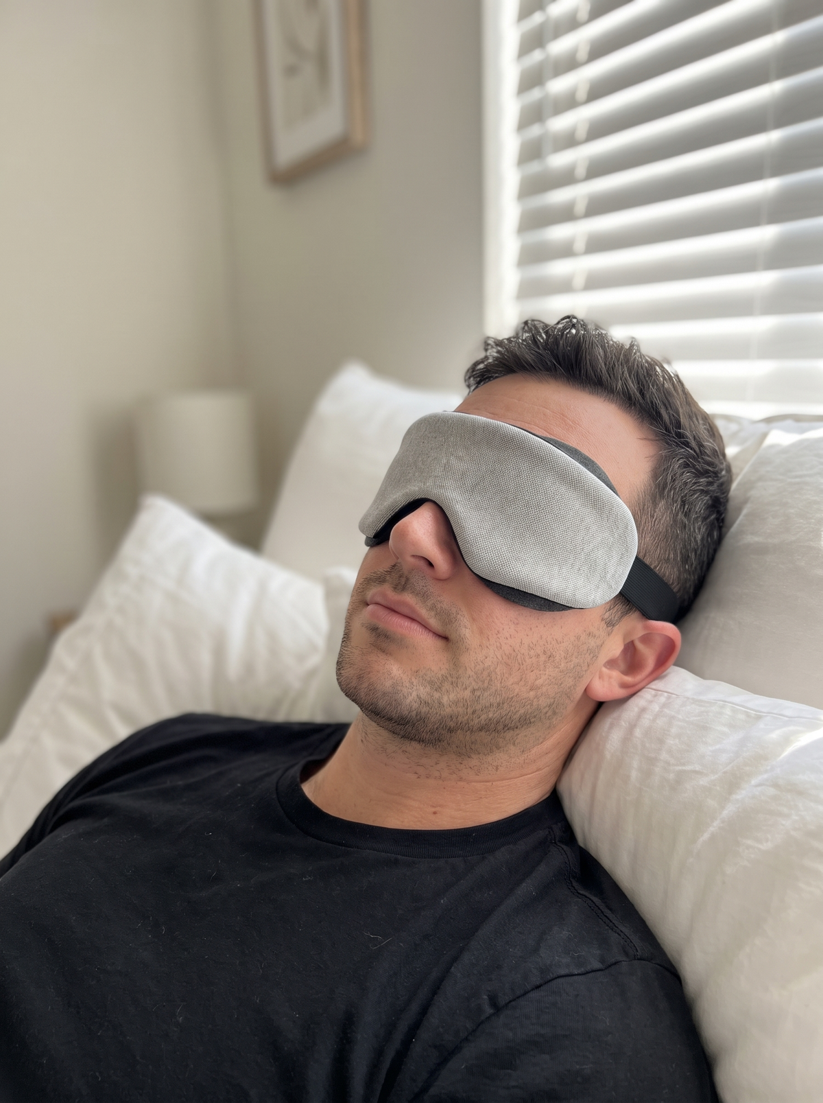 DAYBLIND 3D Contour Blackout Mask worn in bed — grey contoured shell, black strap, morning light blocked